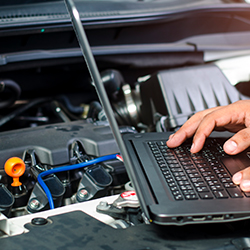 Automobile computer diagnosis. Car mechanic repairer looks for engine failure on diagnostics equipment in vehicle service workshop