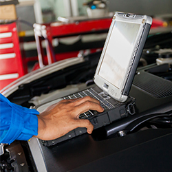 Automobile computer diagnosis. Car mechanic repairer looks for engine failure on diagnostics equipment in vehicle service workshop